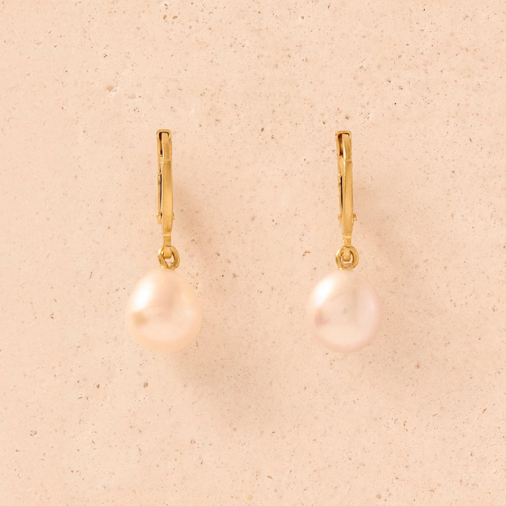Gold earrings with pearls on a beige background