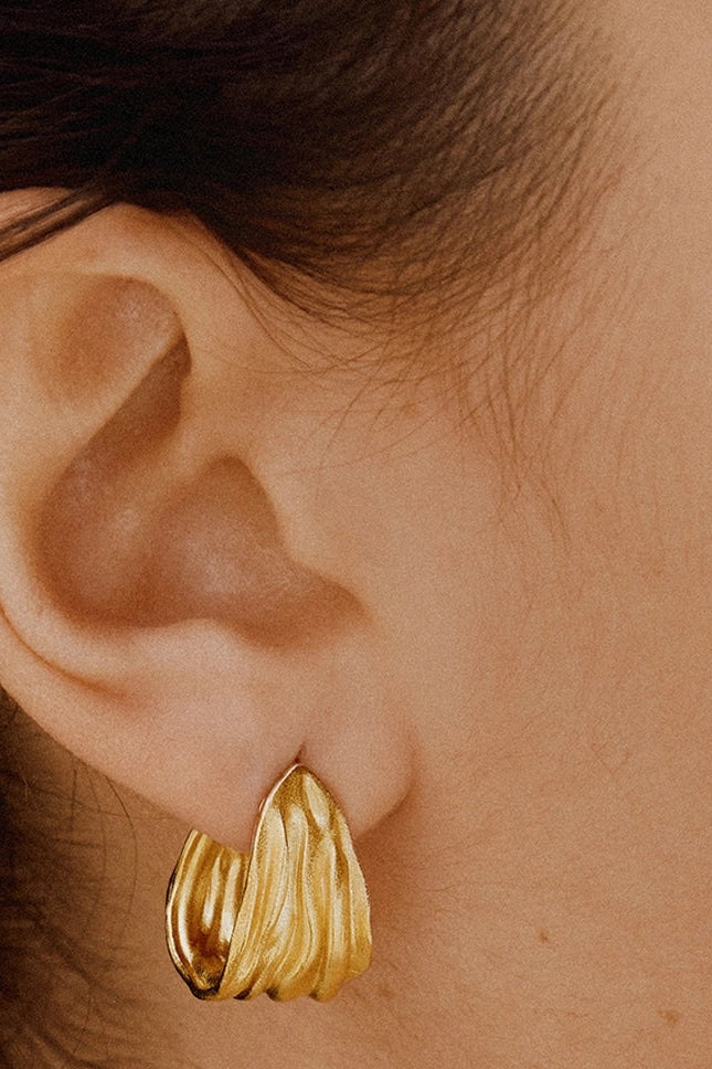 Gold hoop earring worn by a person with dark hair.
