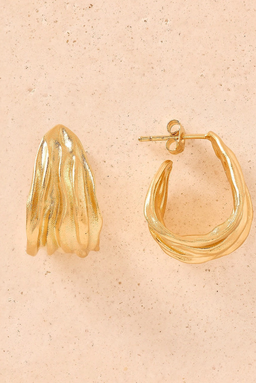 Gold hoop earrings on a beige background