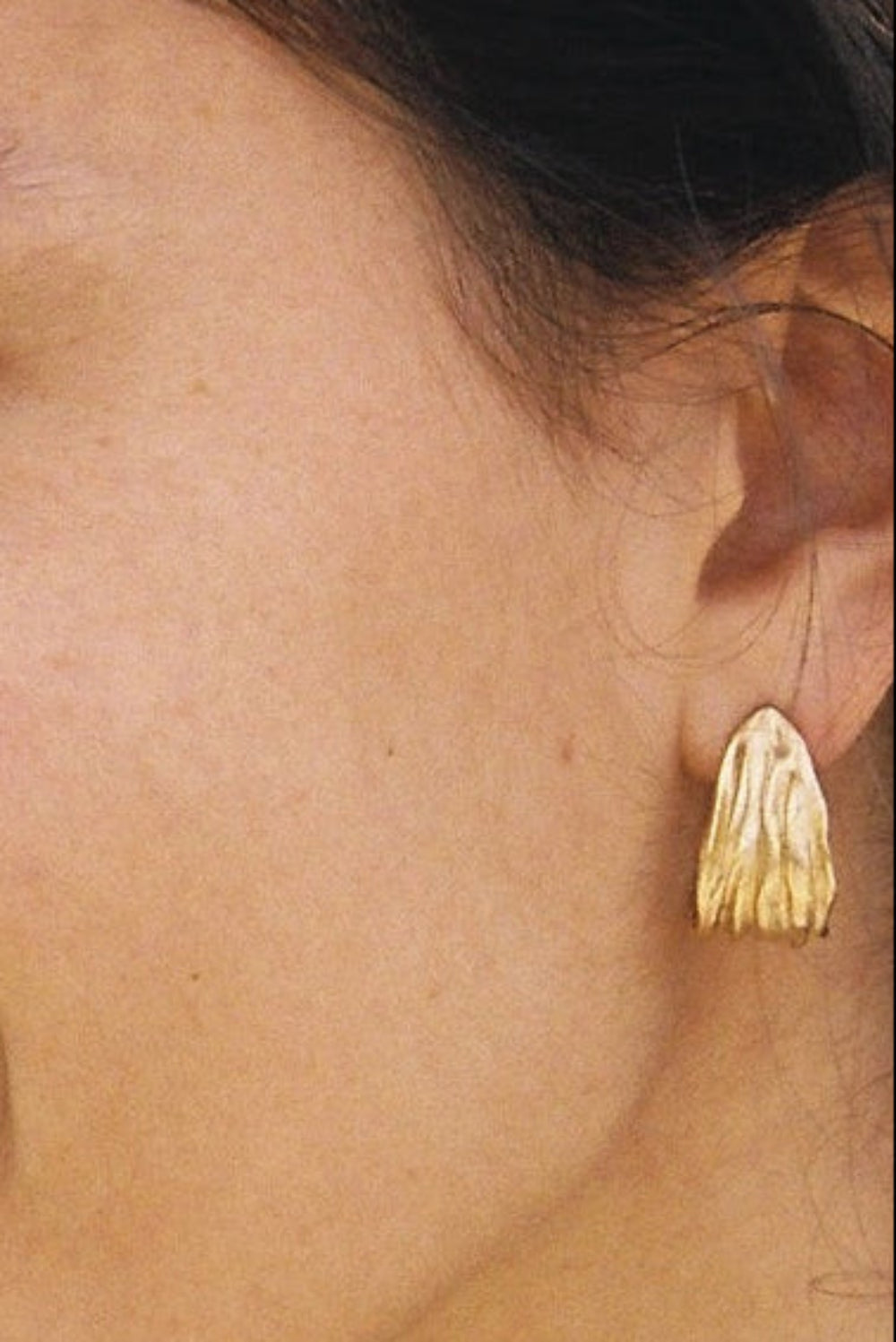 Woman wearing gold earrings with a blurred background