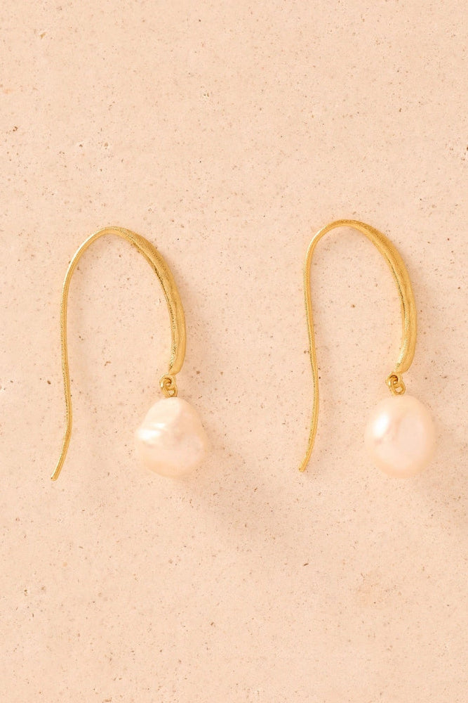Gold earrings with pink pearls on a beige background
