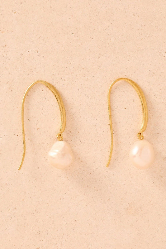 Gold earrings with pink pearls on a beige background